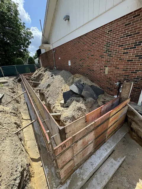 Wall forms set for a foundation along a brick building.