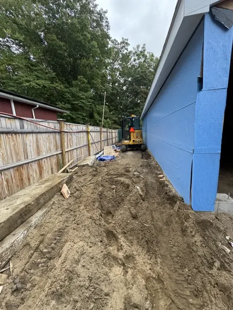 A new wall sheathed and wrapped beside a fence.
