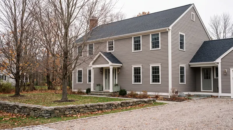 A New England colonial house with new siding, white trim and a newly shingled roof.