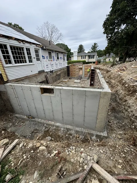 A new poured concrete foundation for a house addition, with the house behind it.